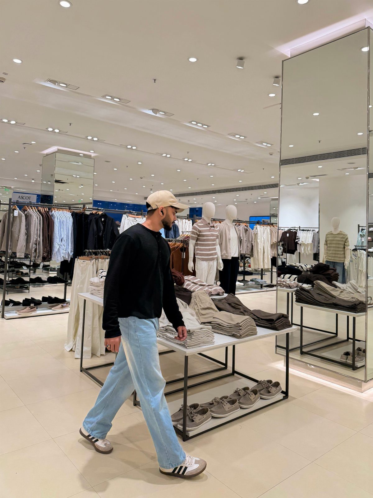 Man in black shirt and light blue jeans wearing white Adidas Samba sneakers
