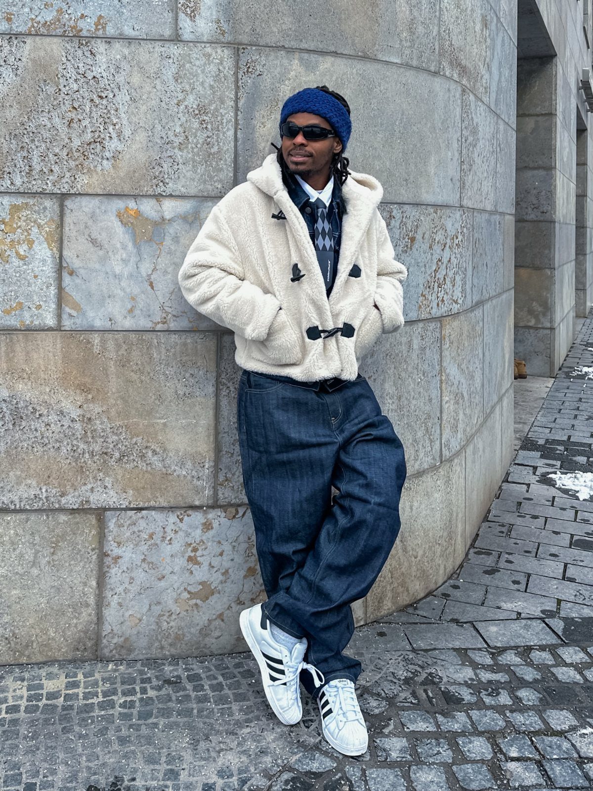 Man in cream teddy coat, blue beanie, and white Adidas Samba sneakers.
