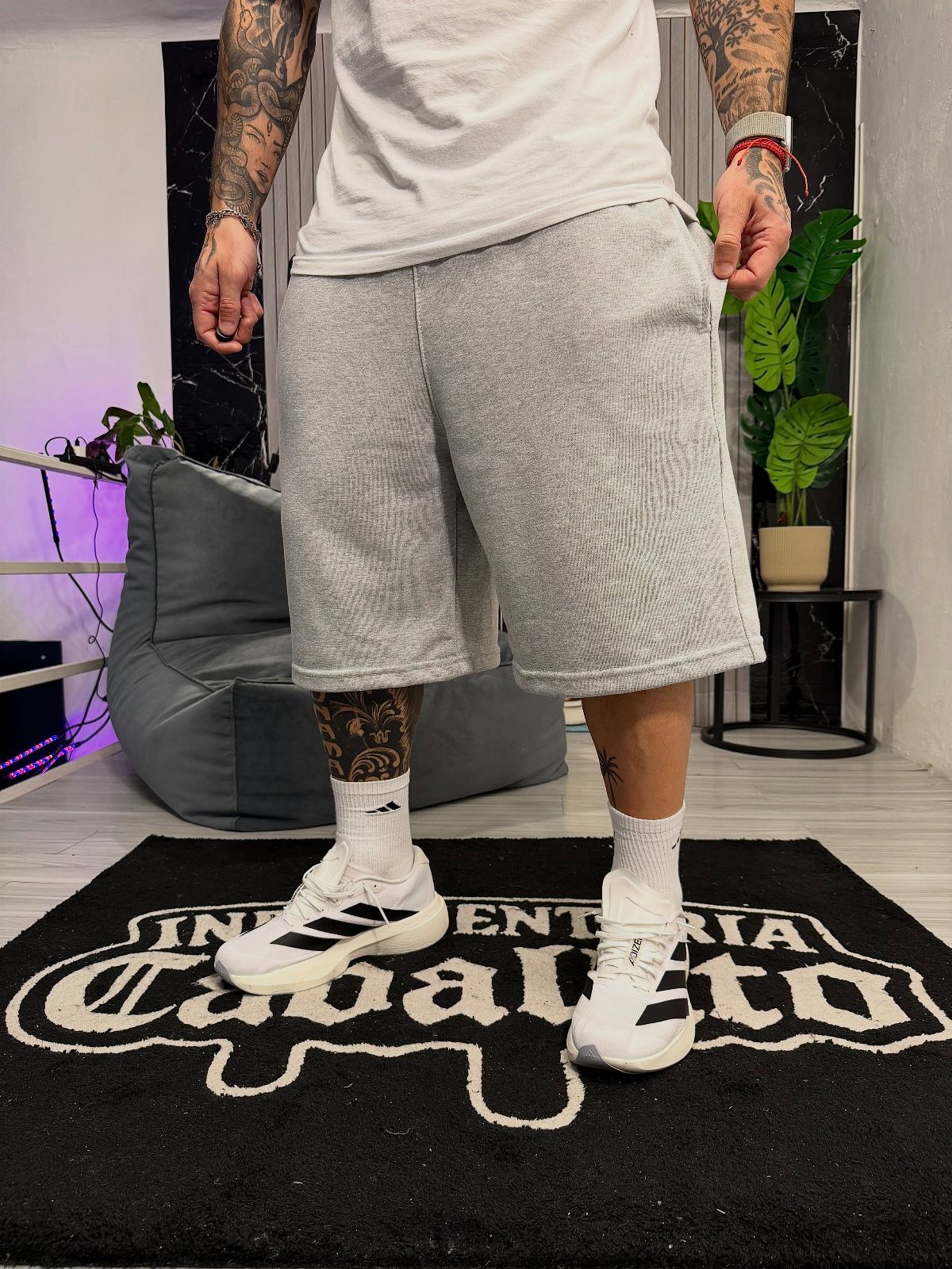 Person wearing grey athletic shorts, a grey t-shirt, and white Adidas sneakers.