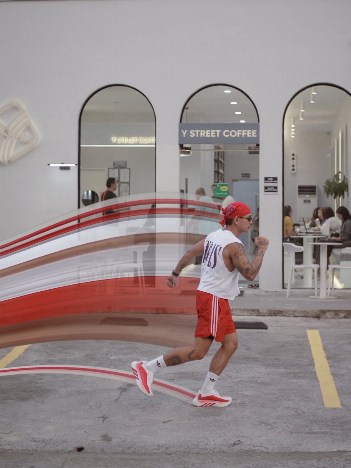 Man running in red athletic shorts, white tank top, and red sneakers.