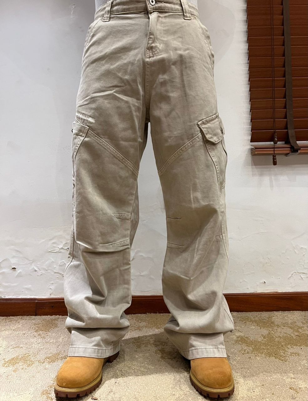Baggy beige cargo pants paired with tan nubuck boots on a carpeted floor.