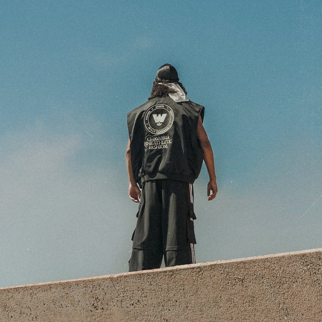 Man from behind wearing a black cargo vest and baggy cargo pants.