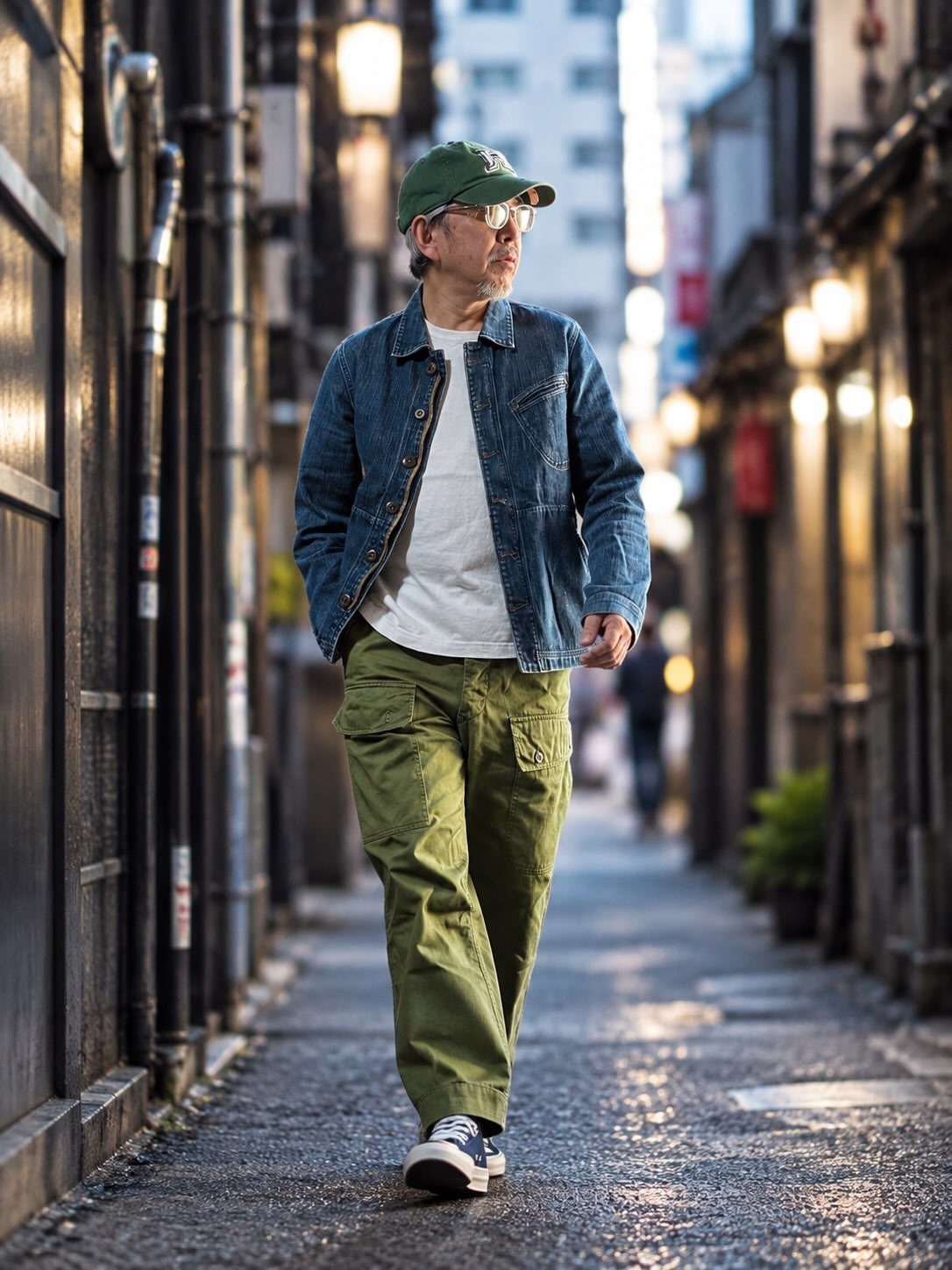 Man in olive green cargo pants and blue sneakers walking in a city alley
