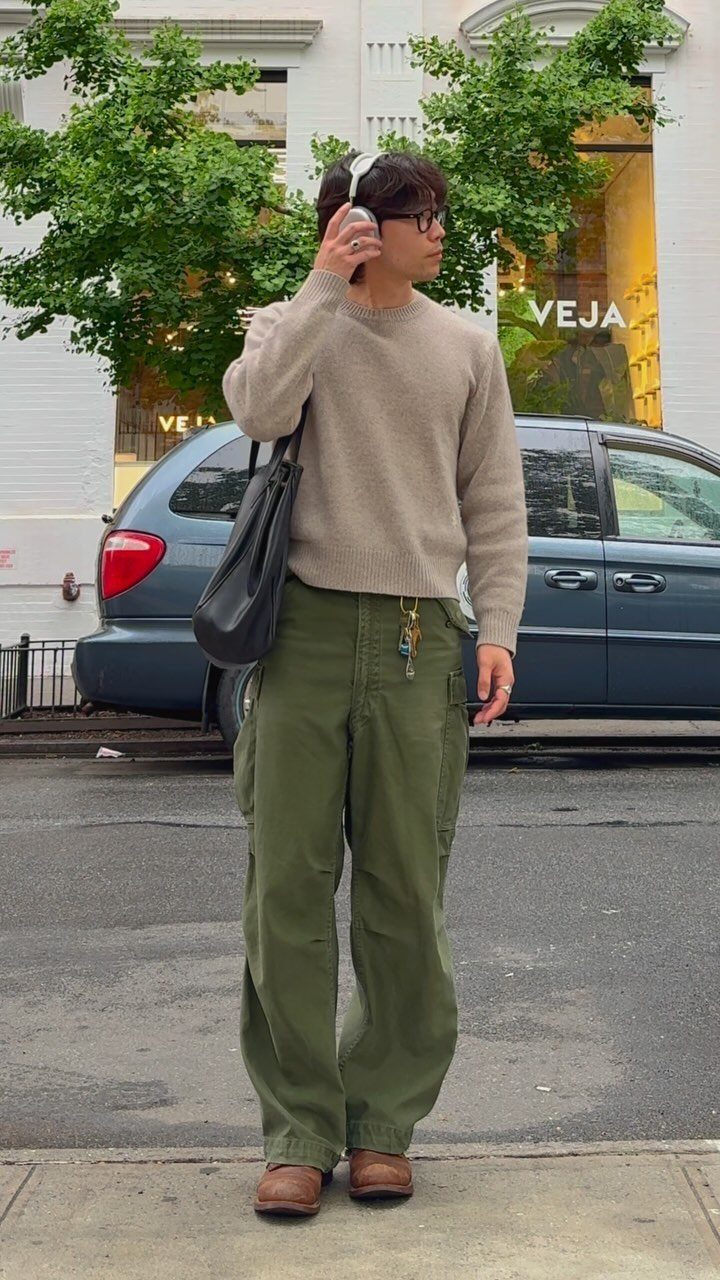 Man wearing a beige sweater and olive green baggy cargo pants on a street