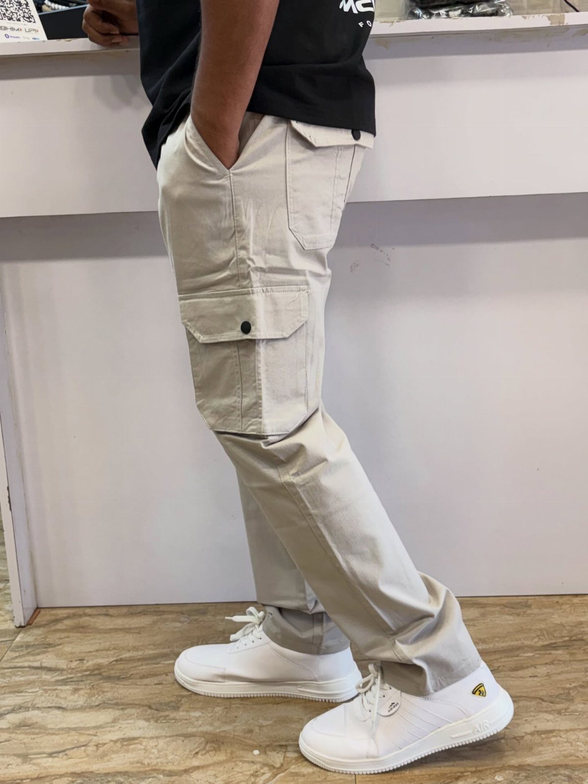 Beige cargo pants paired with a black t-shirt and white sneakers.
