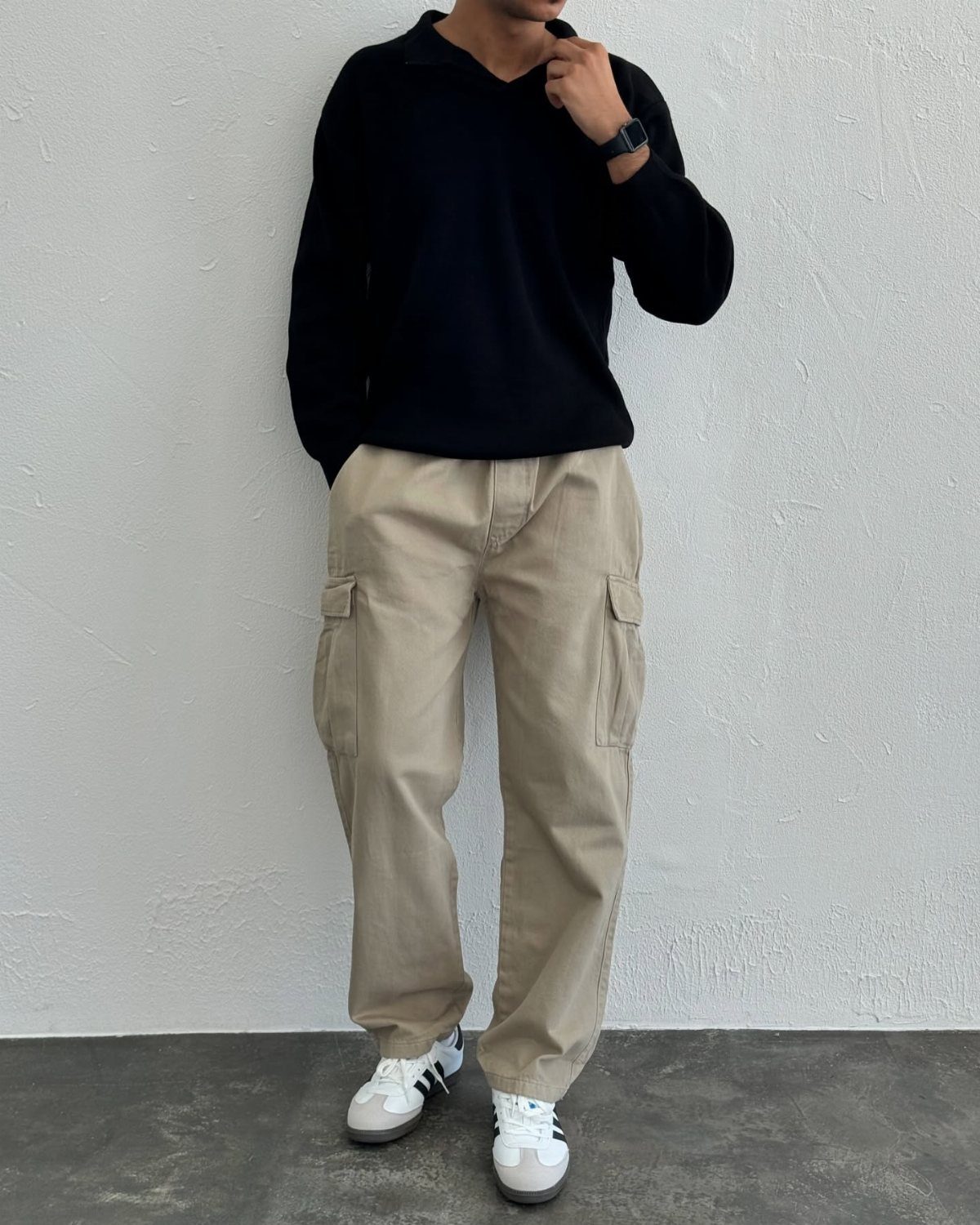 Person wearing a black polo shirt, beige baggy cargo pants, and white sneakers.