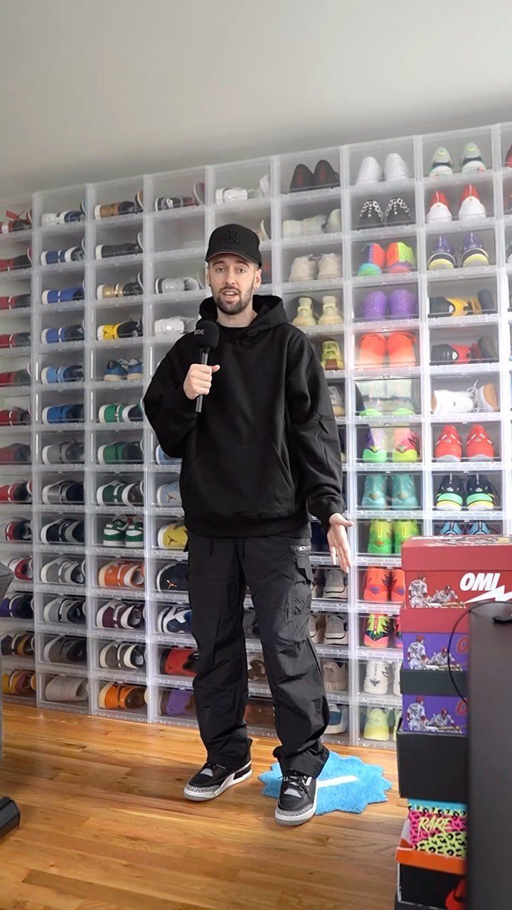 Man wearing all black outfit with baggy cargo pants in front of shoe wall