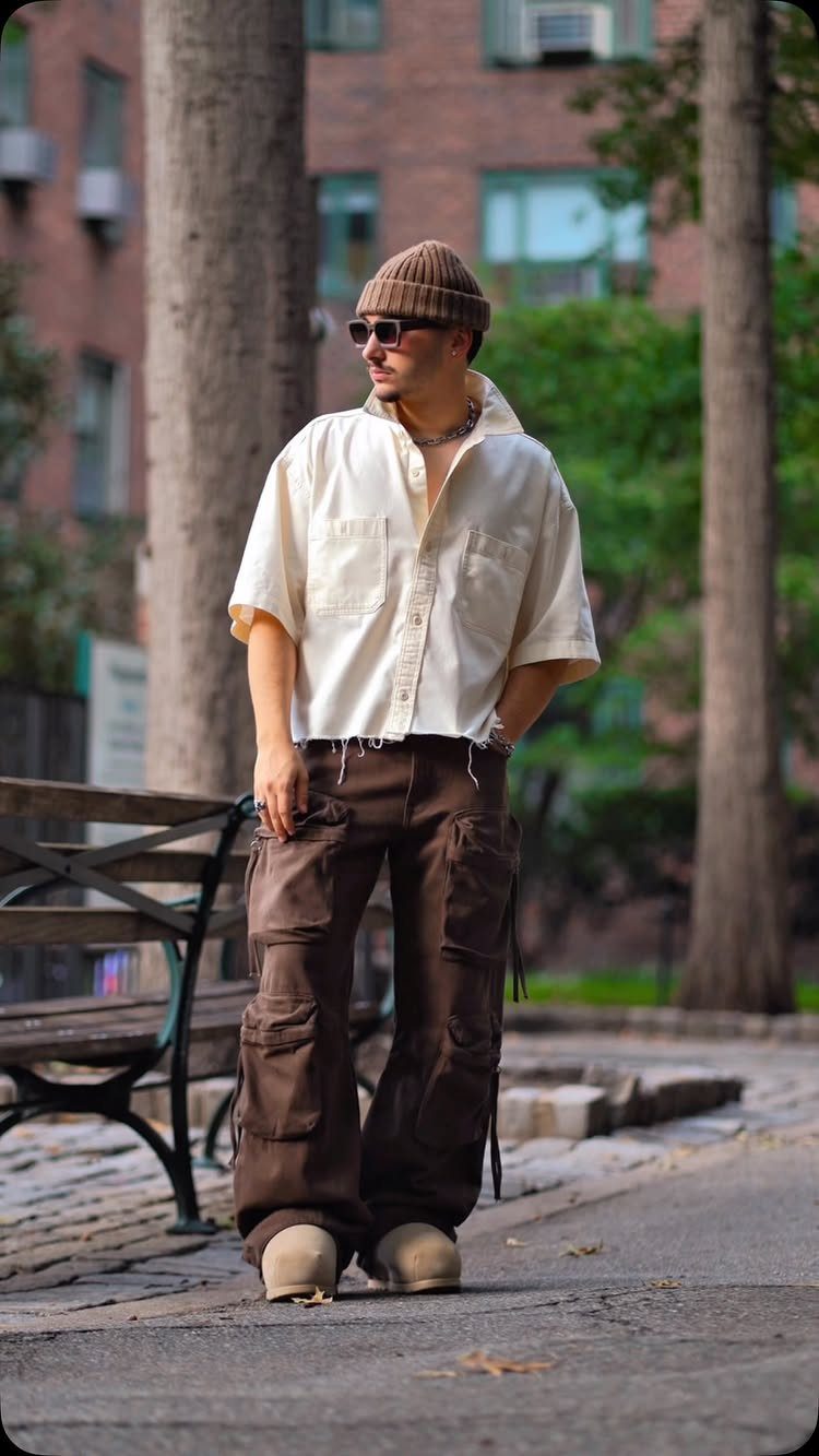 Man wearing brown baggy cargo pants, tan boots, and a cream shirt outdoors.