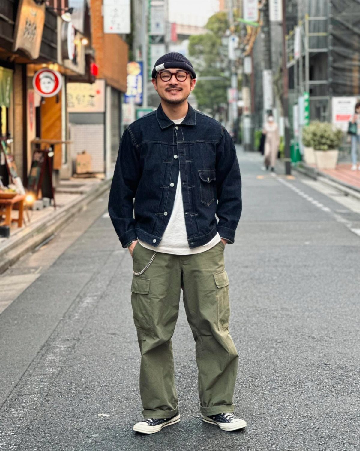 Man wearing a dark denim jacket and olive green baggy cargo pants on street