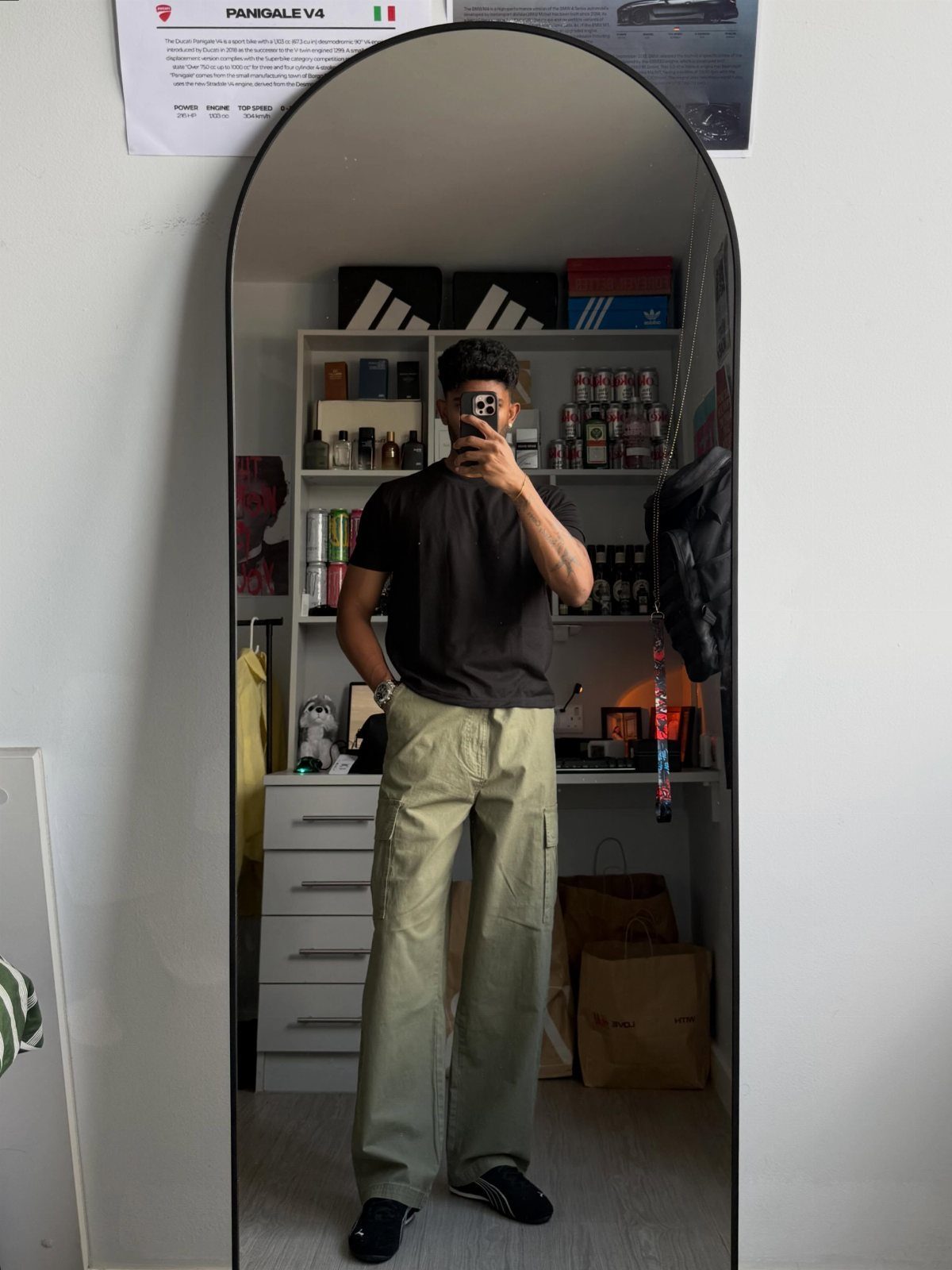 Man in black fitted t-shirt and olive green baggy cargo pants mirror selfie