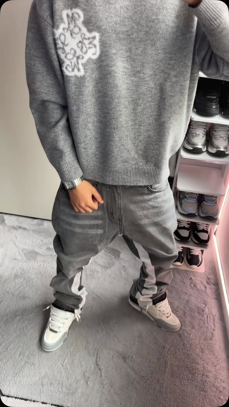 White casual sneakers worn with grey baggy jeans and an oversized grey sweater.