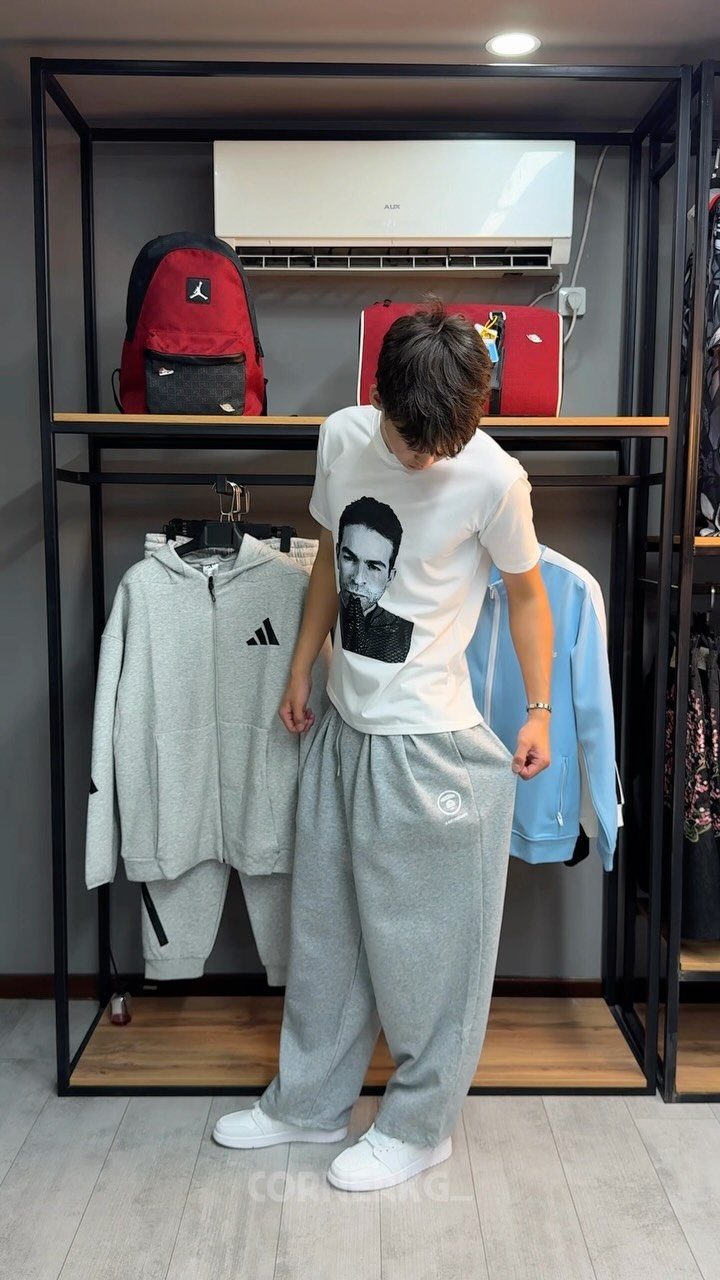 Person wearing baggy grey sweatpants and white sneakers in a clothing store.