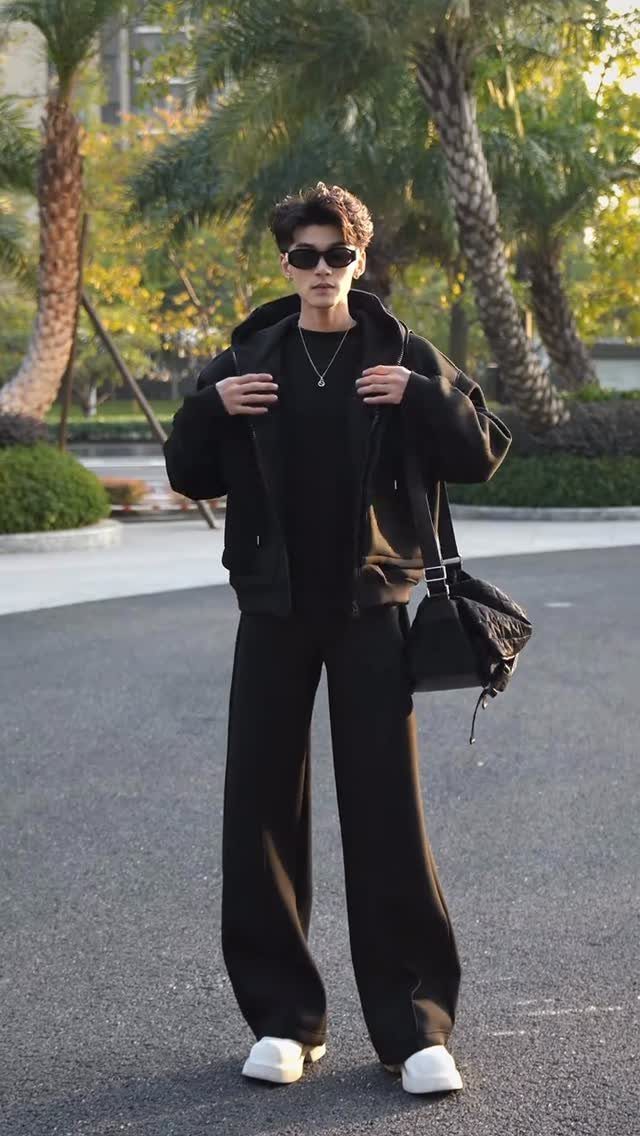 Person in black cropped jacket over longer tee and wide-leg black trousers.