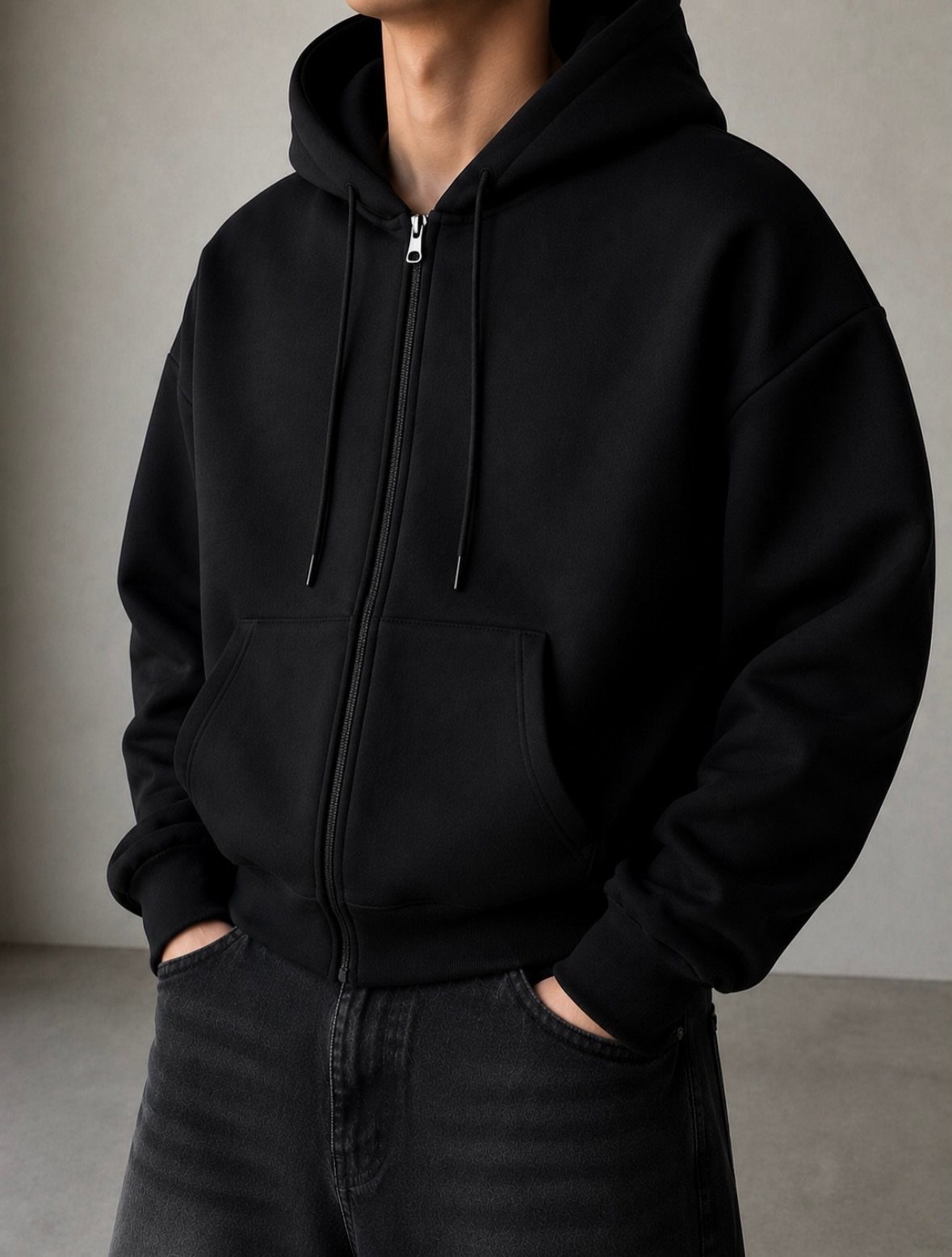 Person wearing a black oversized zip-up hoodie and black denim jeans.