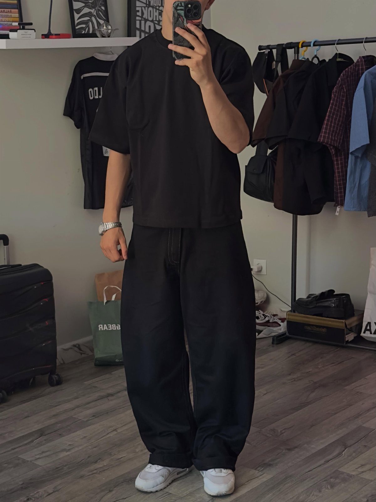 Person wearing an oversized black t-shirt and baggy black sweatpants with white sneakers.