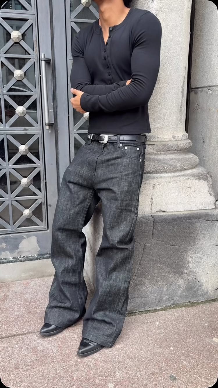 Man in black henley and dark grey wide-leg jeans wearing black leather boots.