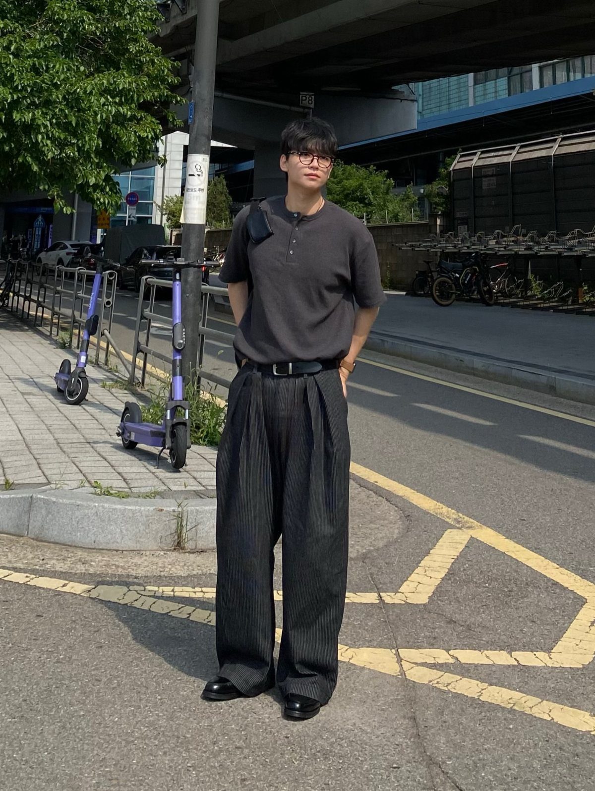 Person wearing charcoal pinstripe trousers and black loafers standing on a city street