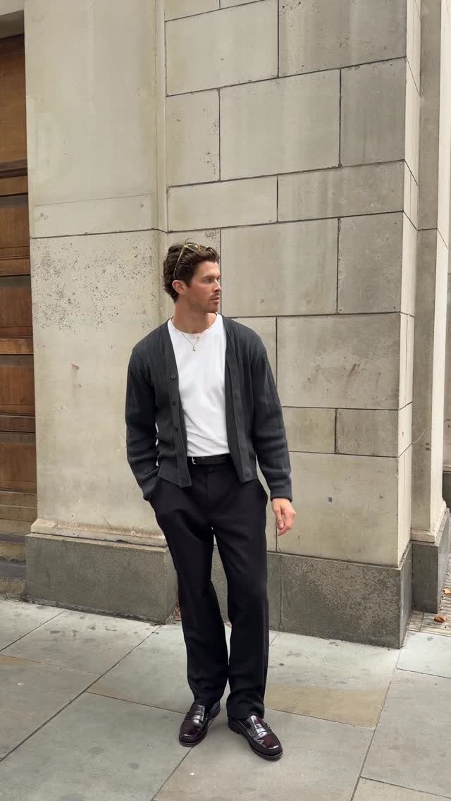 Man wearing black loafers, black trousers, white t-shirt, and dark grey cardigan.