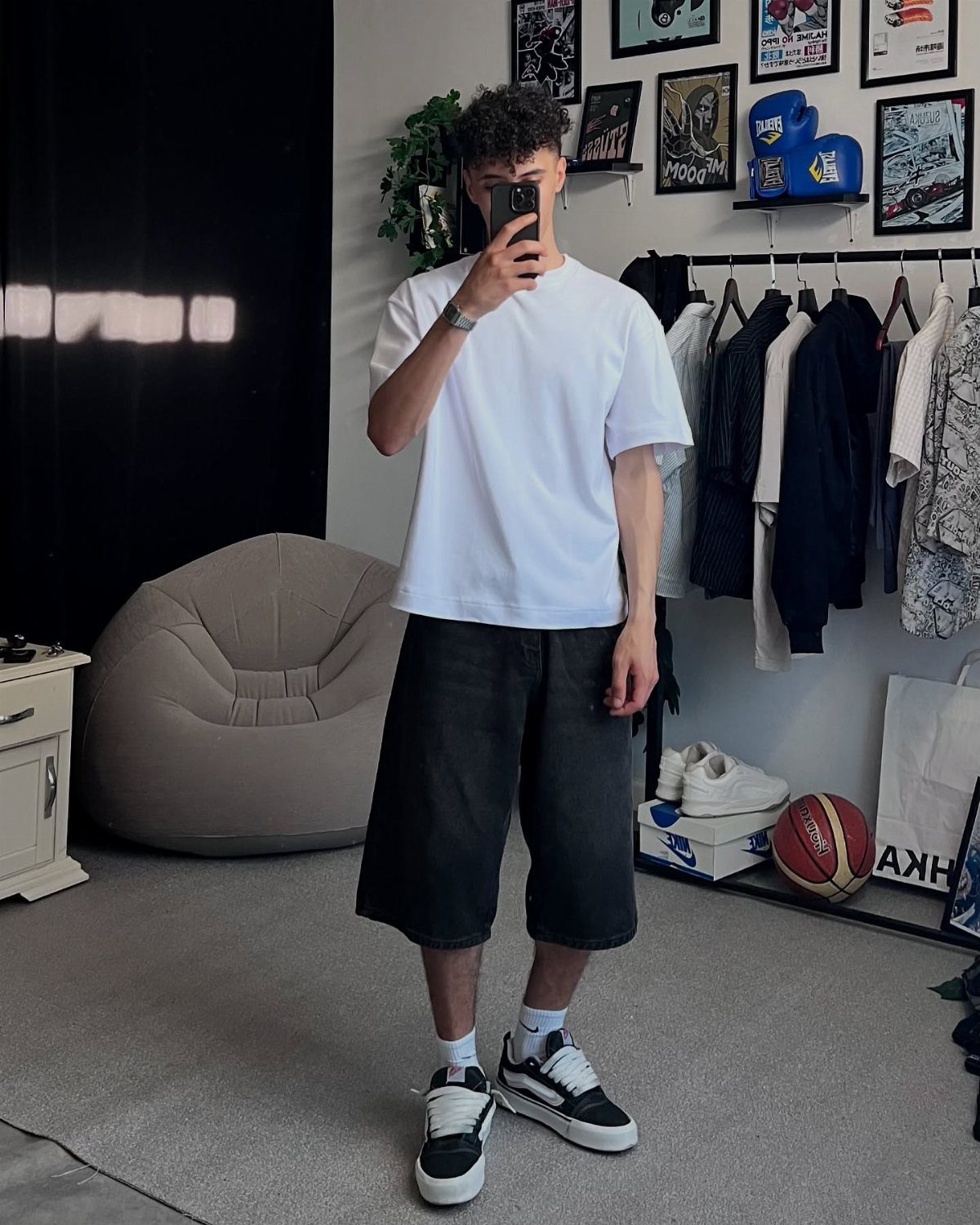 Man wearing white t-shirt, black shorts, and black and white fashion sneakers.