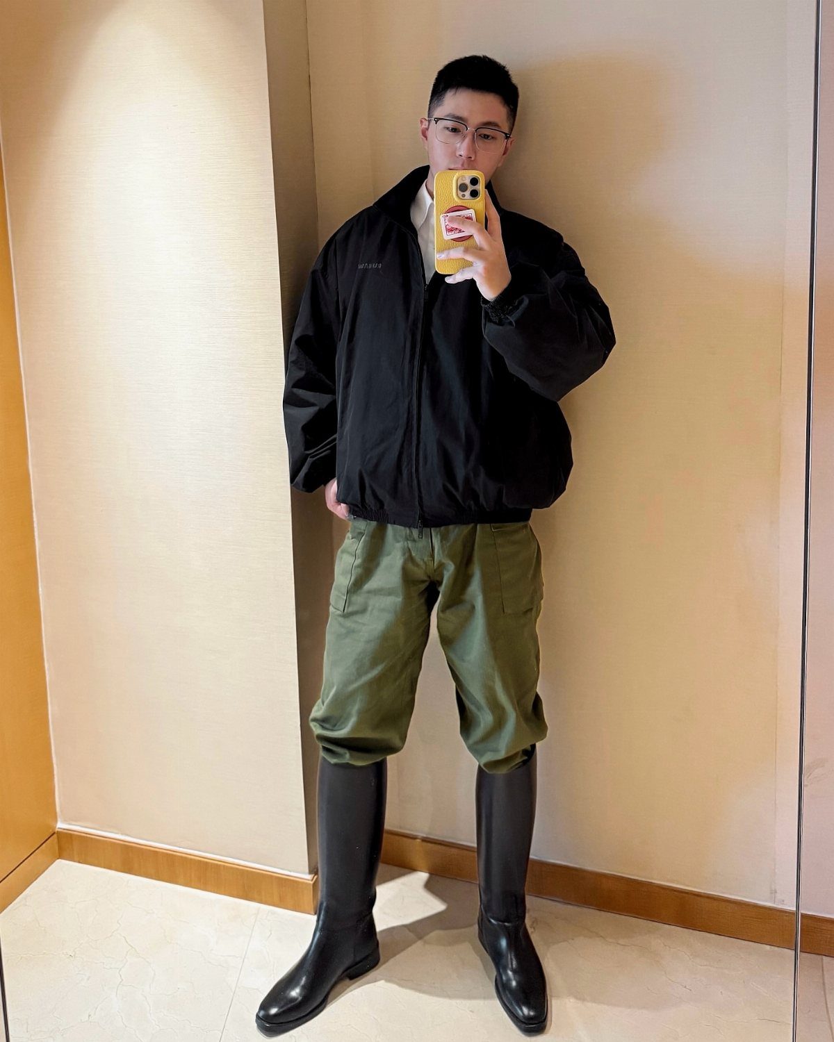 Man wearing black jacket, olive green cargo pants, and tall black leather boots.