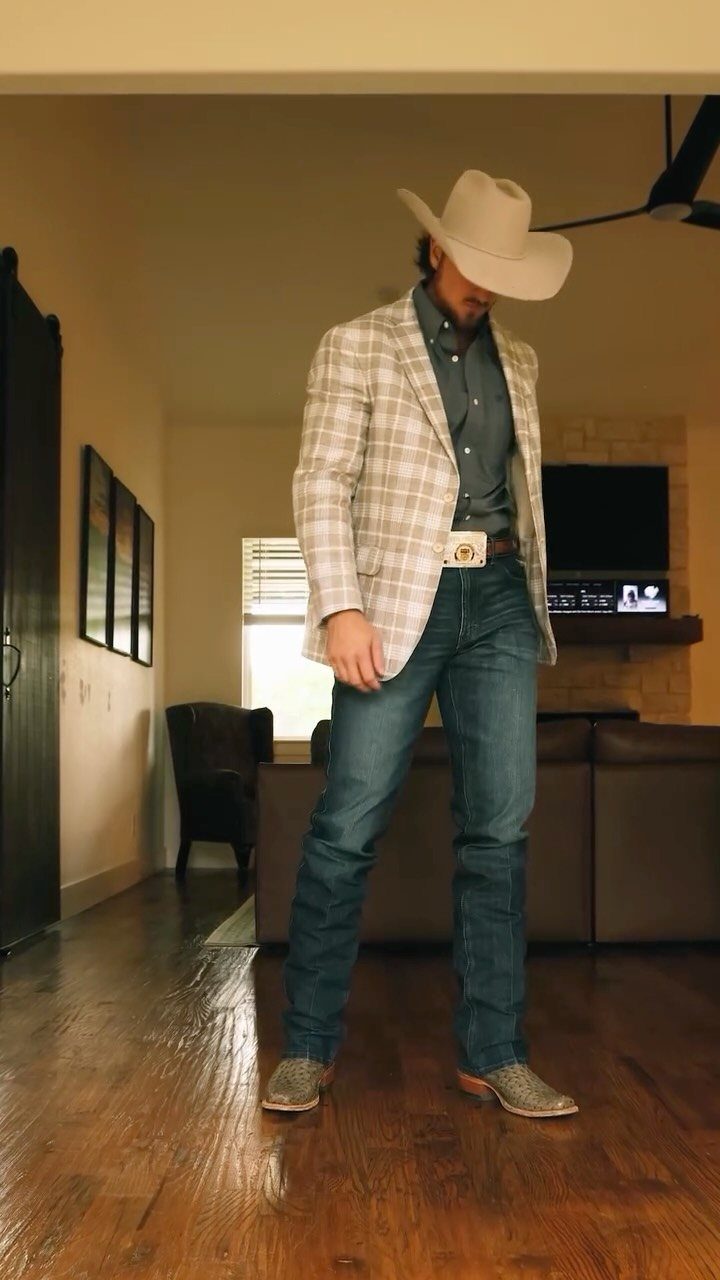 Man in cowboy hat, plaid blazer, blue jeans, and tan cowboy boots.