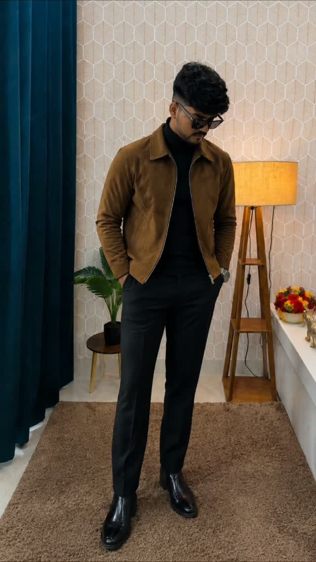 Man in brown suede jacket and black dress pants wearing polished black boots.