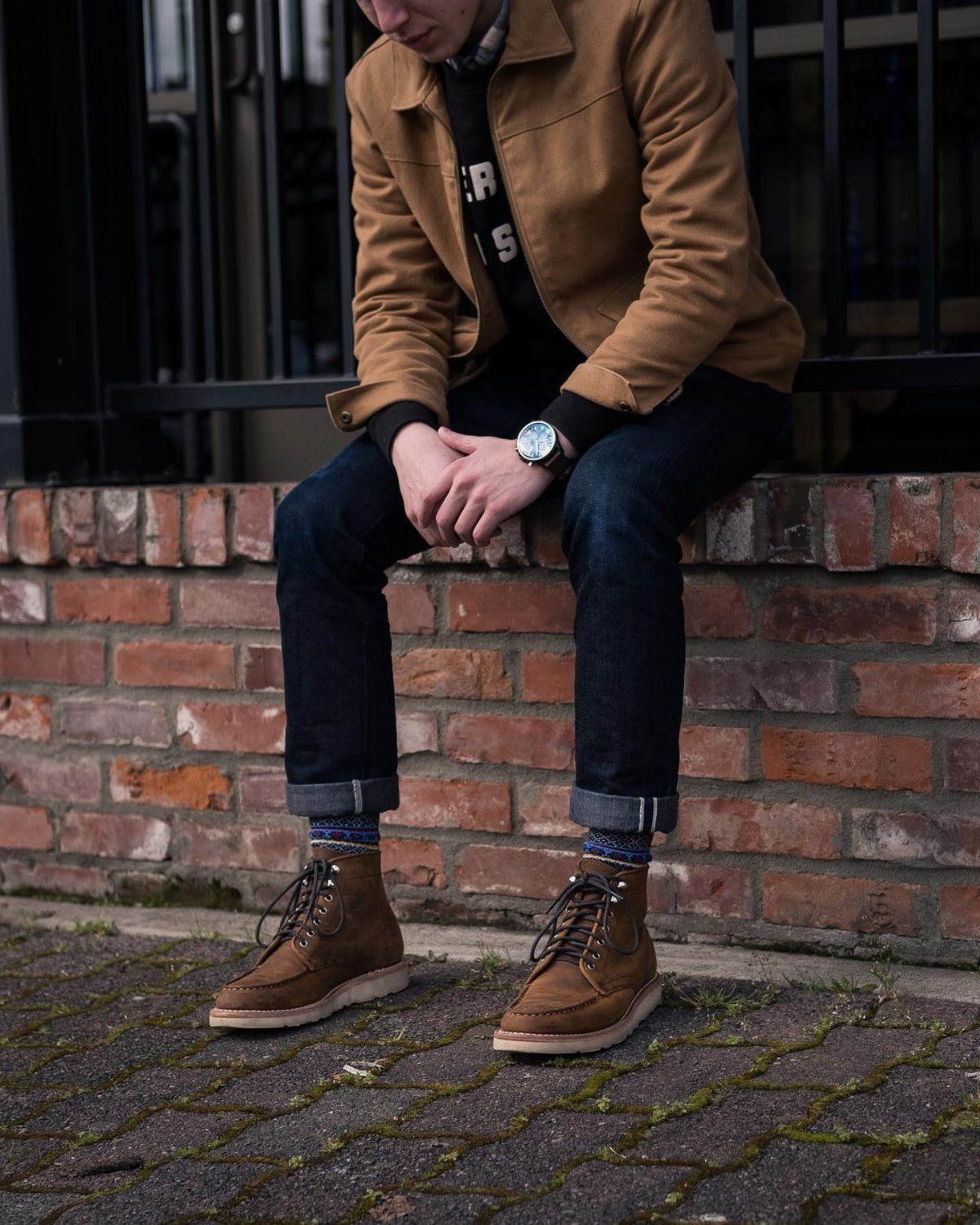 Brown lace-up boots, dark blue cuffed jeans, and a tan suede jacket.