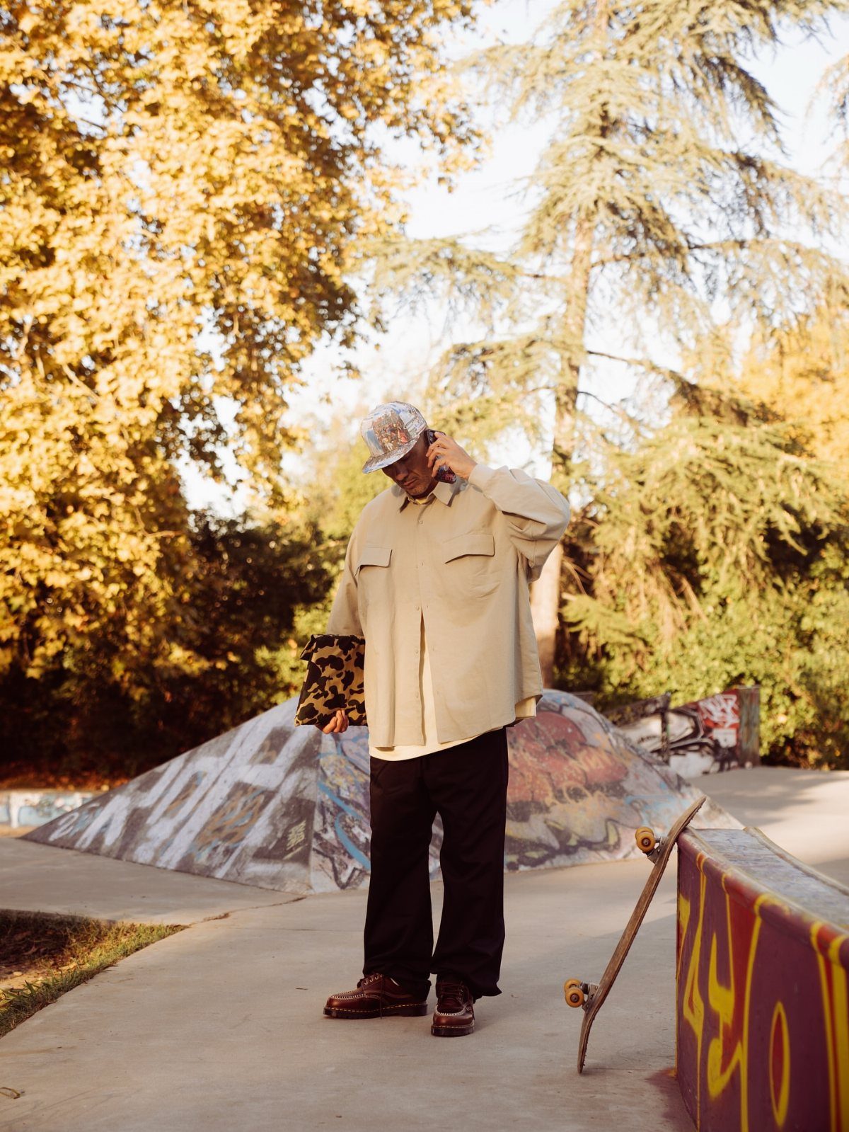Person in beige shirt and black pants wearing brown leather boots at skatepark