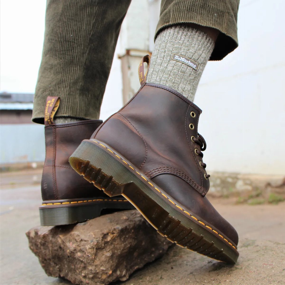 Brown leather lace-up boots with yellow stitching worn with olive corduroy trousers.
