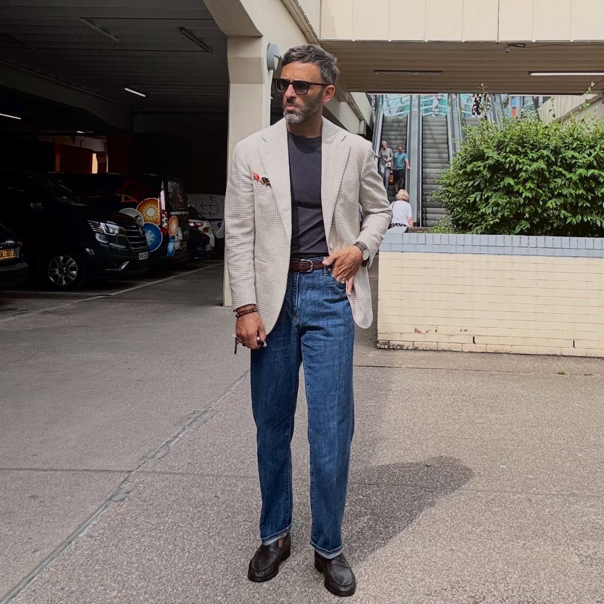Man wearing a light blazer, blue jeans, and dark brown leather loafers outdoors.