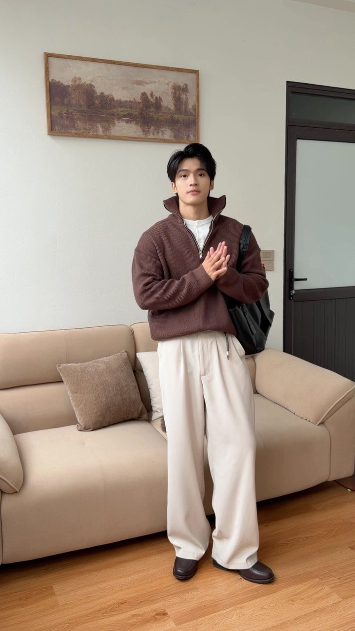 Man wearing a brown quarter-zip sweater, cream wide-leg trousers, and dark brown loafers.