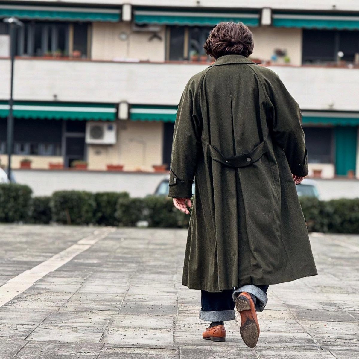 Man from behind wearing olive trench coat and chunky brown leather derby shoes