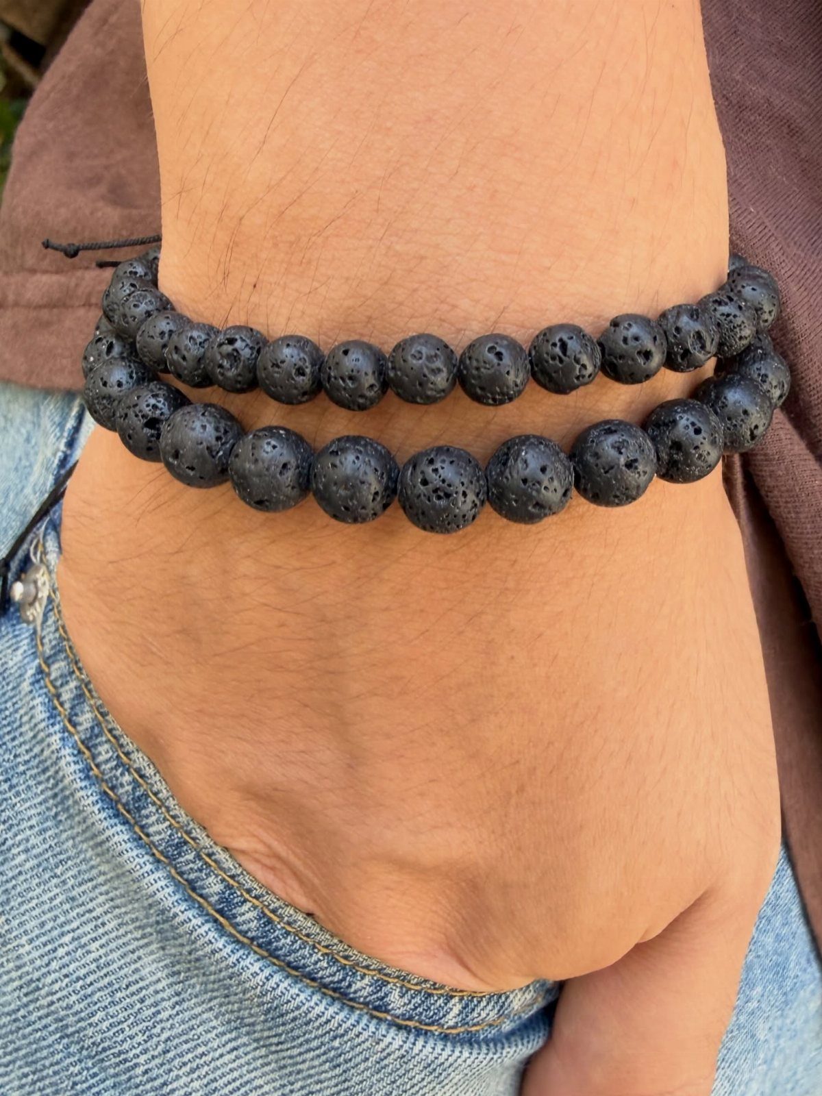 Two black porous lava stone bead bracelets on a man's wrist