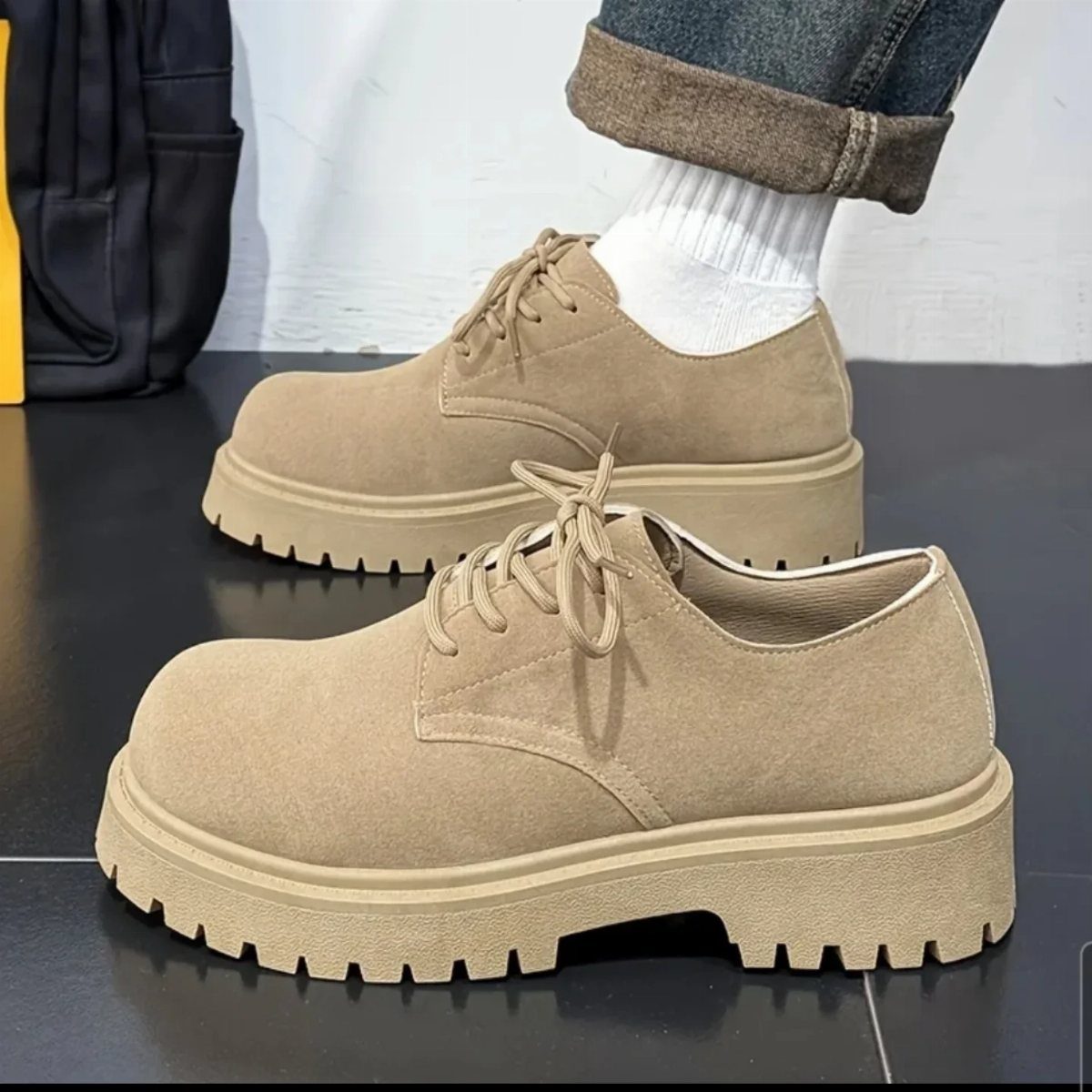 Tan suede derby shoes with thick soles paired with cuffed blue jeans