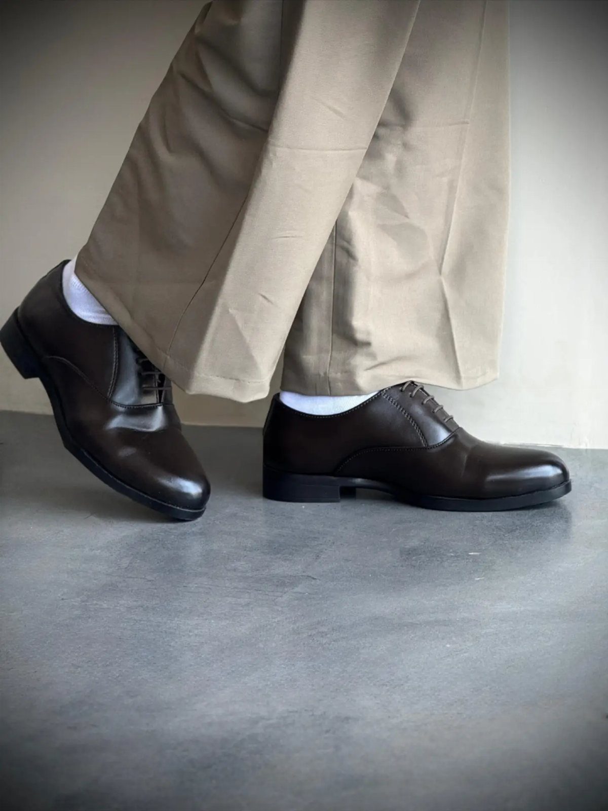 Dark brown leather derby shoes paired with beige chino trousers and white socks.