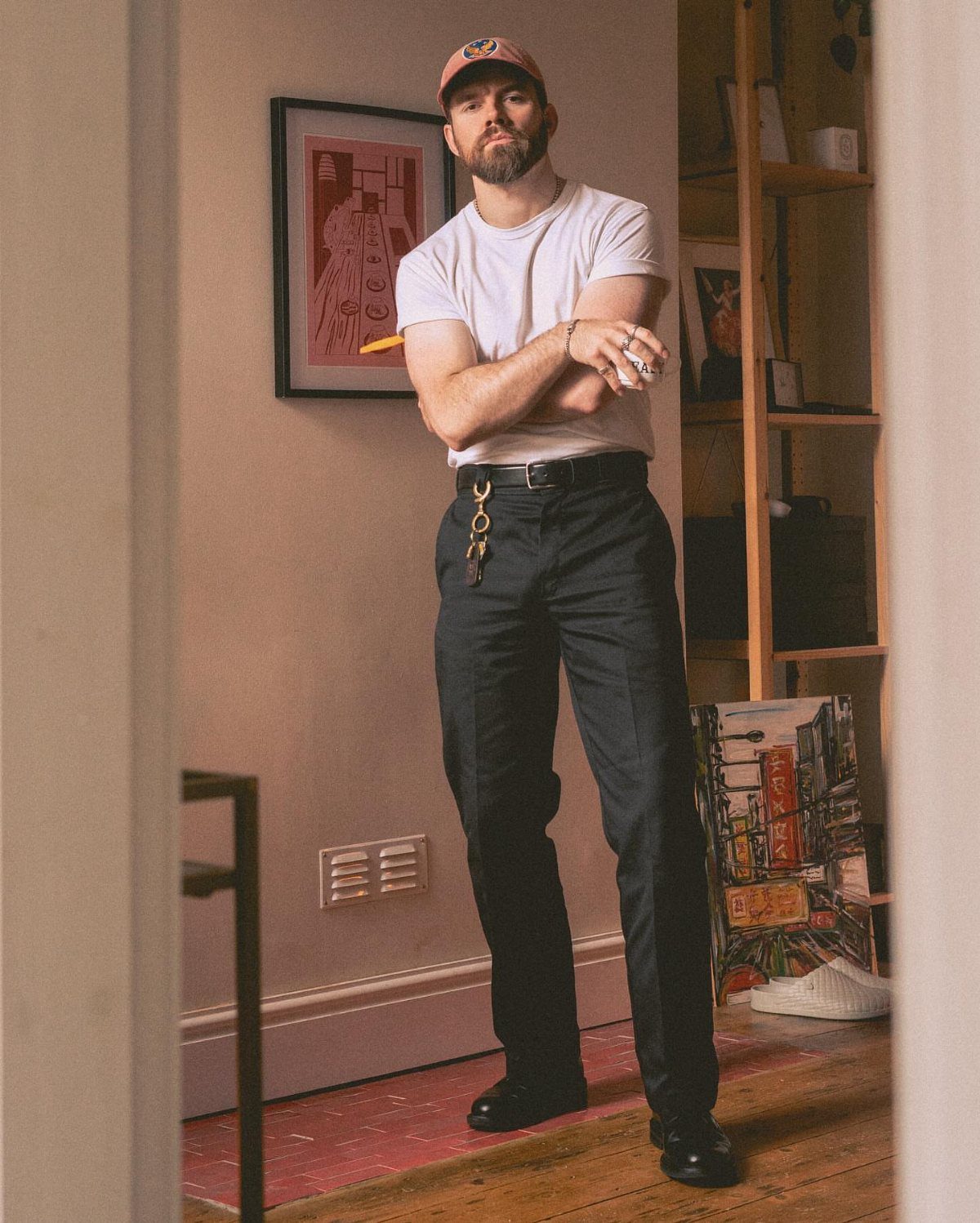 Man in white t-shirt and black trousers wearing black leather derby shoes.