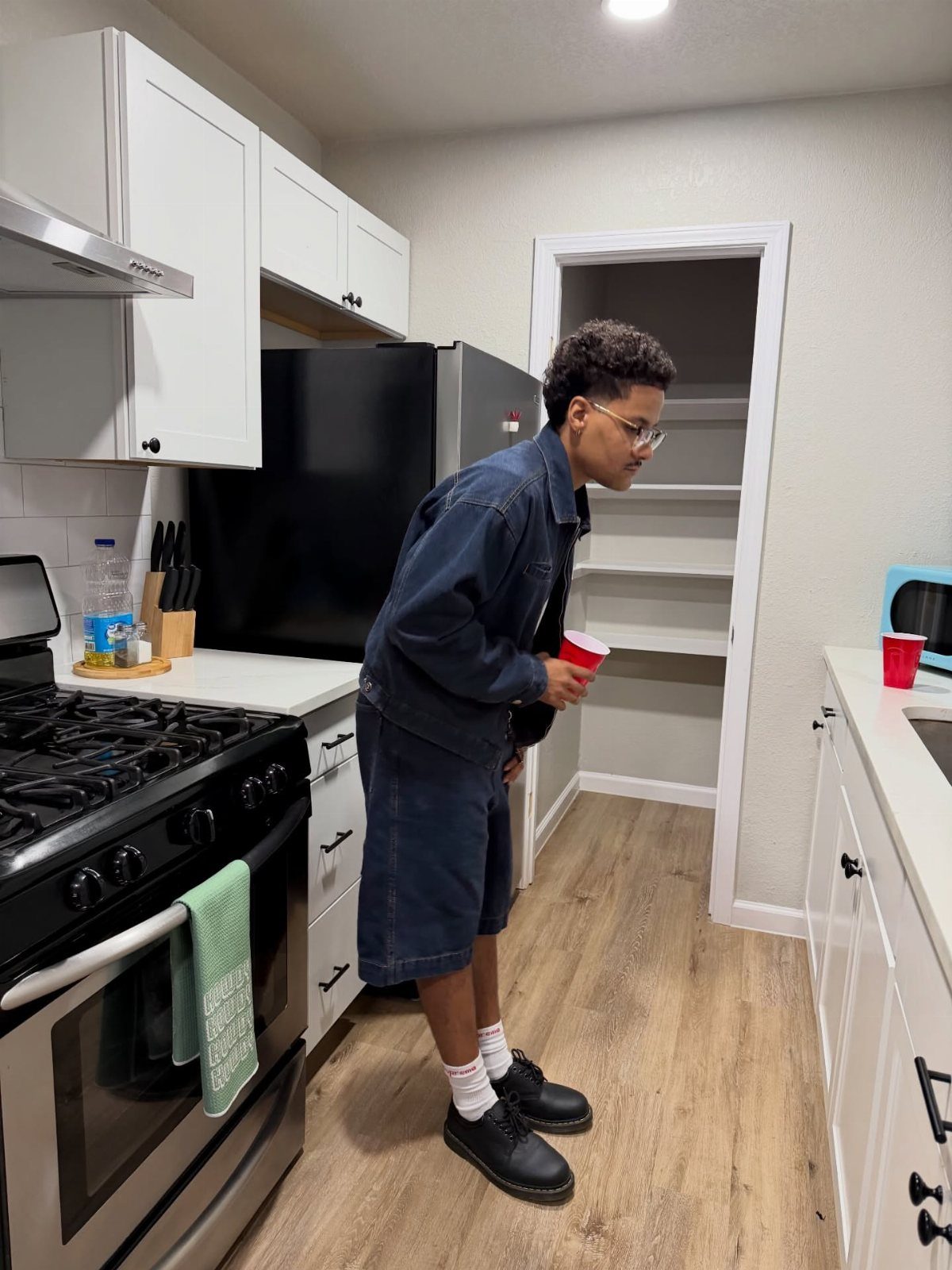 Person in denim jacket and shorts wearing black combat boots in a kitchen