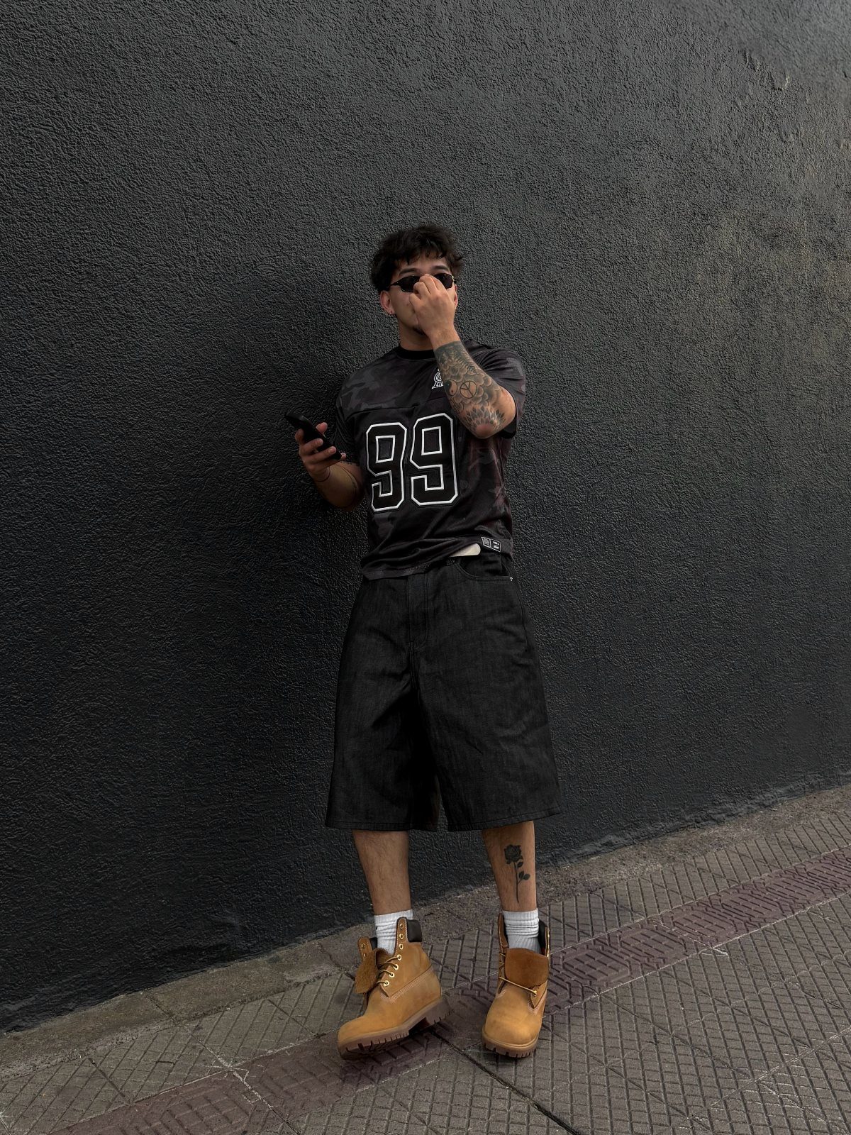 Person wearing a black graphic t-shirt with number 99 and tan boots.