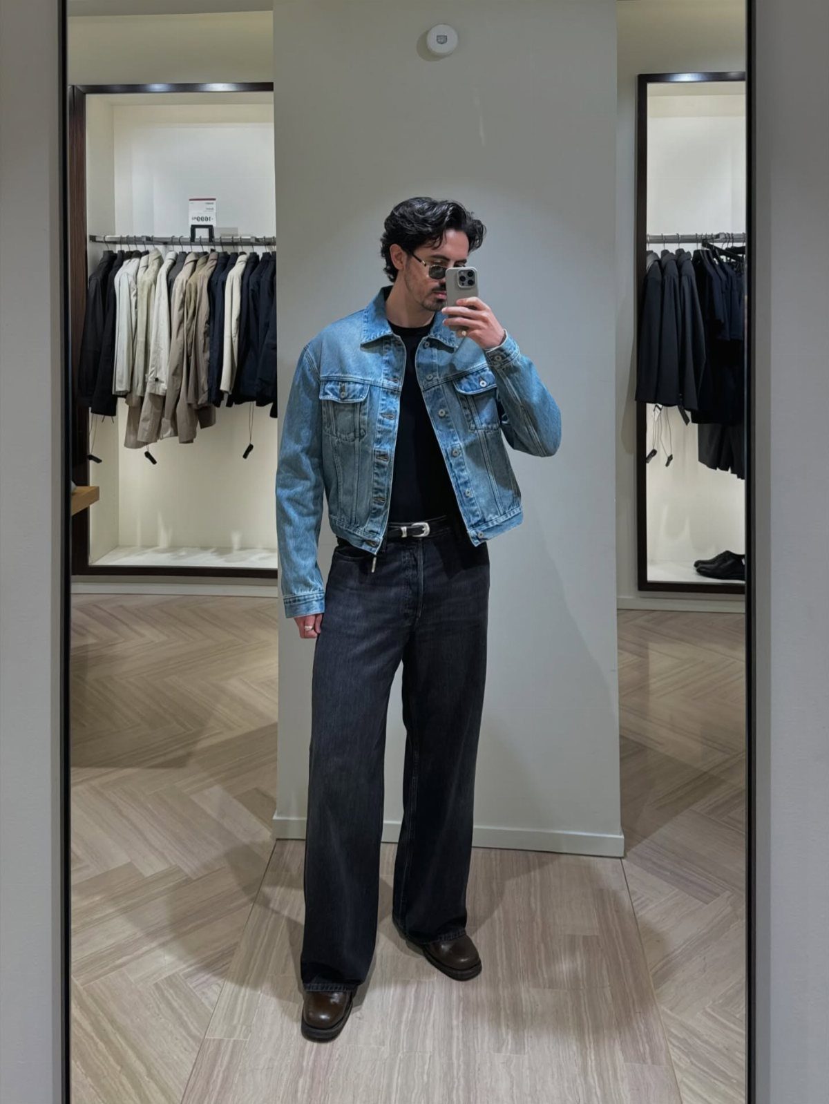 Man wearing a light blue denim jacket, black wide-leg jeans, and brown leather boots.