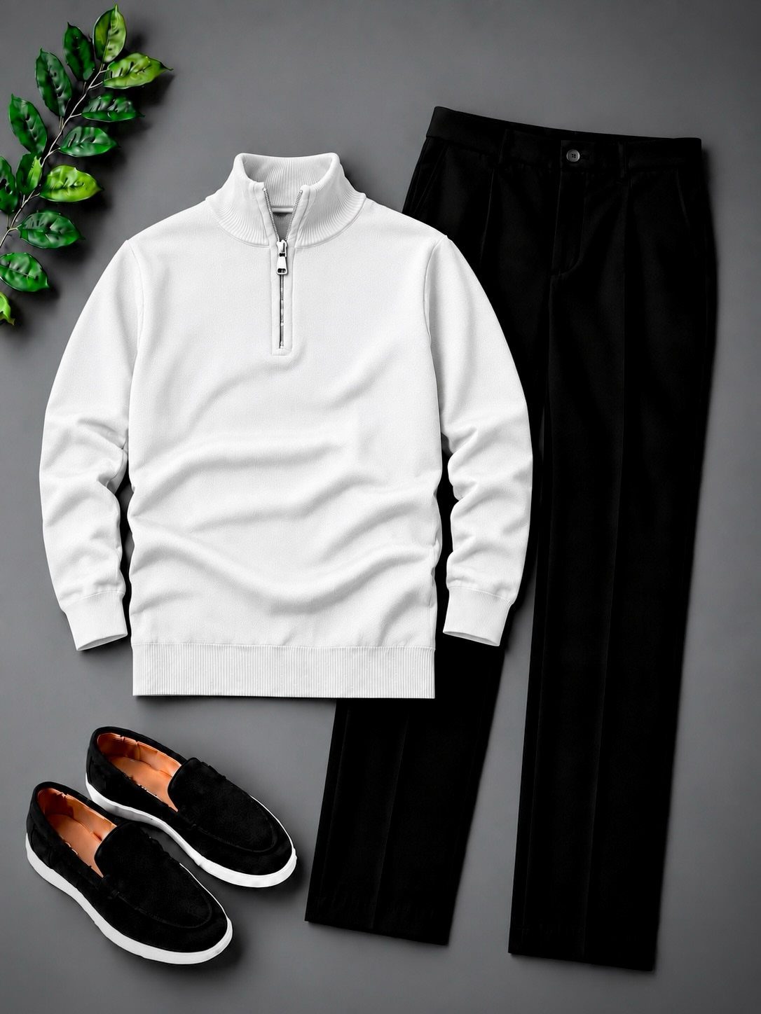 Black suede loafers paired with a white sweater and black trousers on grey.