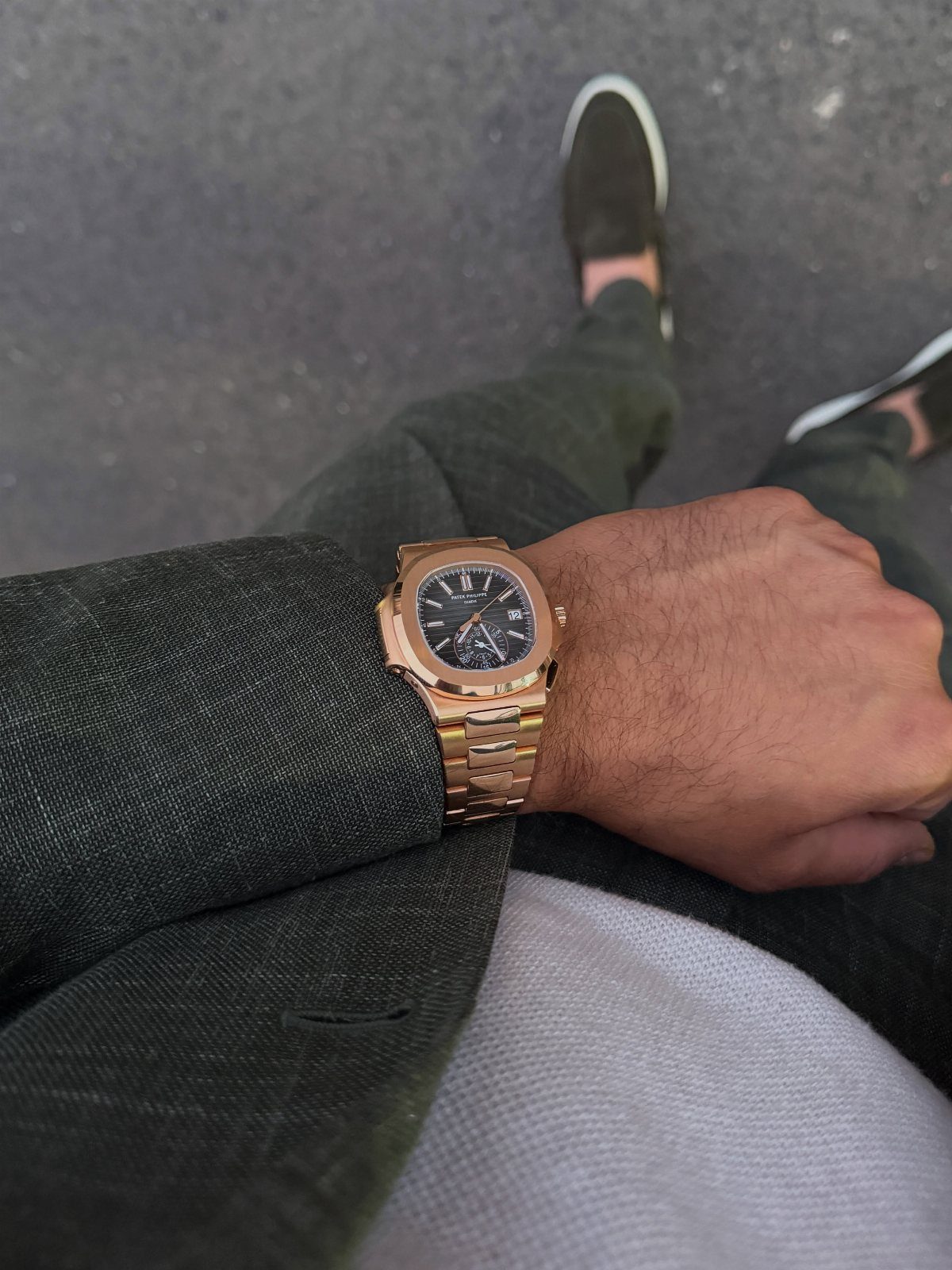 Gold watch on a wrist paired with a green blazer and white shirt.