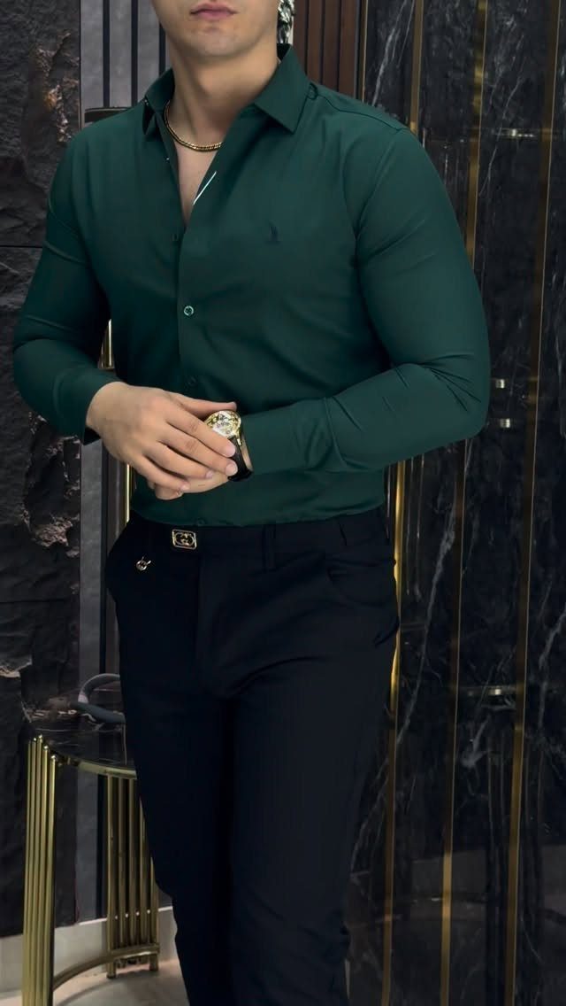 Man in green shirt and black trousers wearing a gold wrist watch