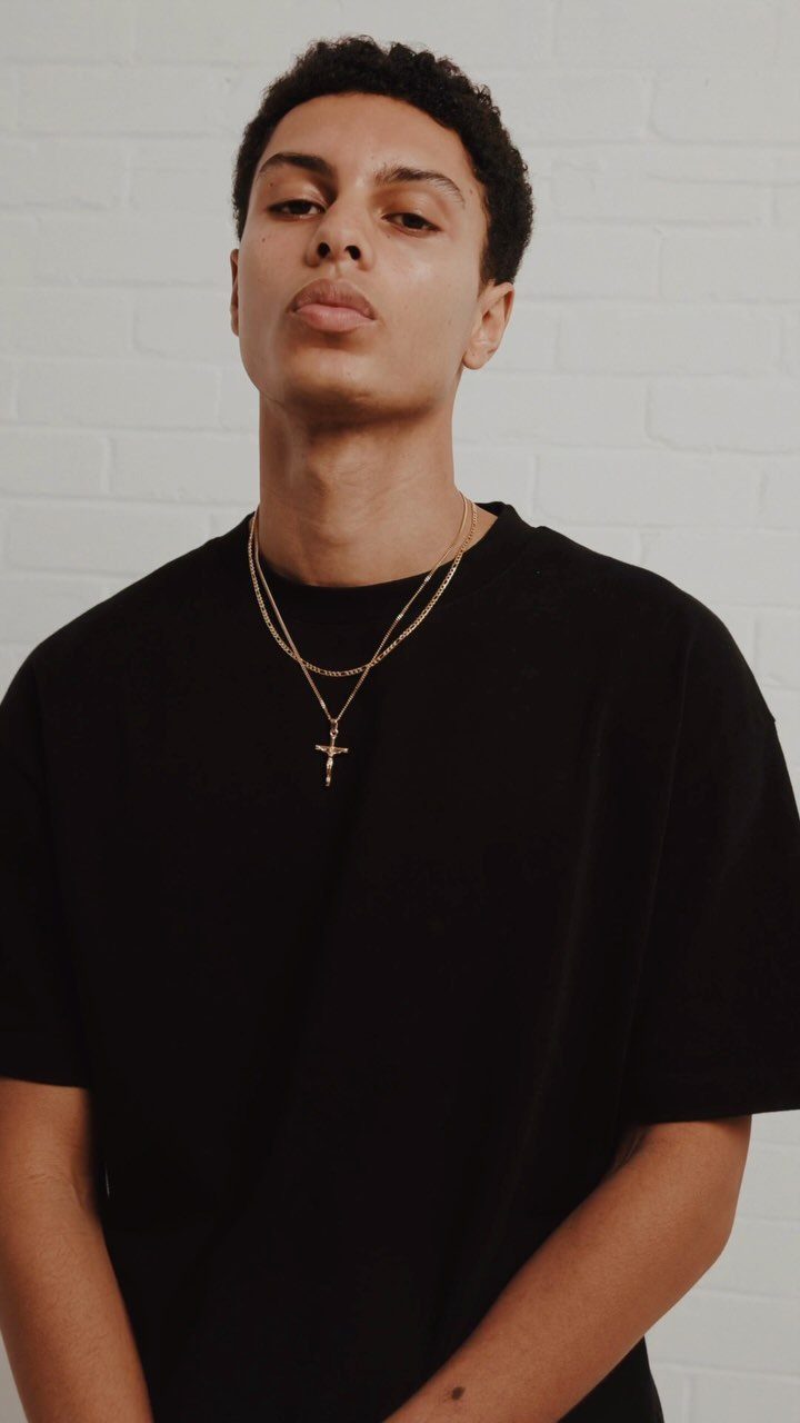 Man wearing layered gold necklaces with a cross pendant and black t-shirt