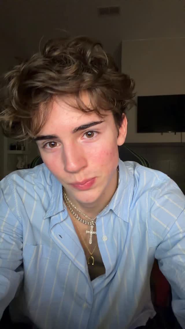 Young man wearing three layered gold necklaces with a blue striped shirt