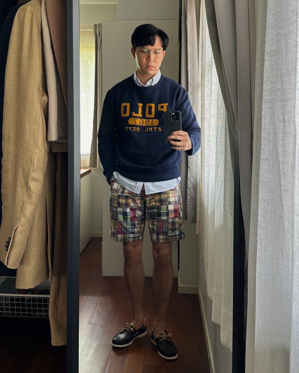 Man wearing navy sweatshirt, colorful plaid shorts, and brown leather boat shoes.