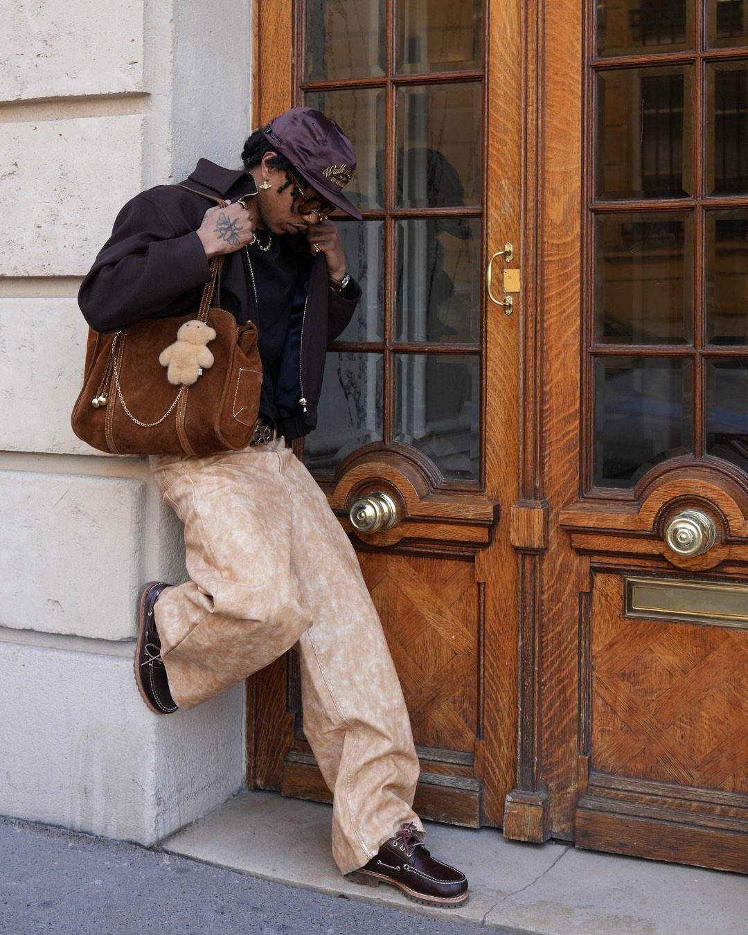 Person wearing brown boat shoes, tan patterned trousers, and a dark brown hoodie.