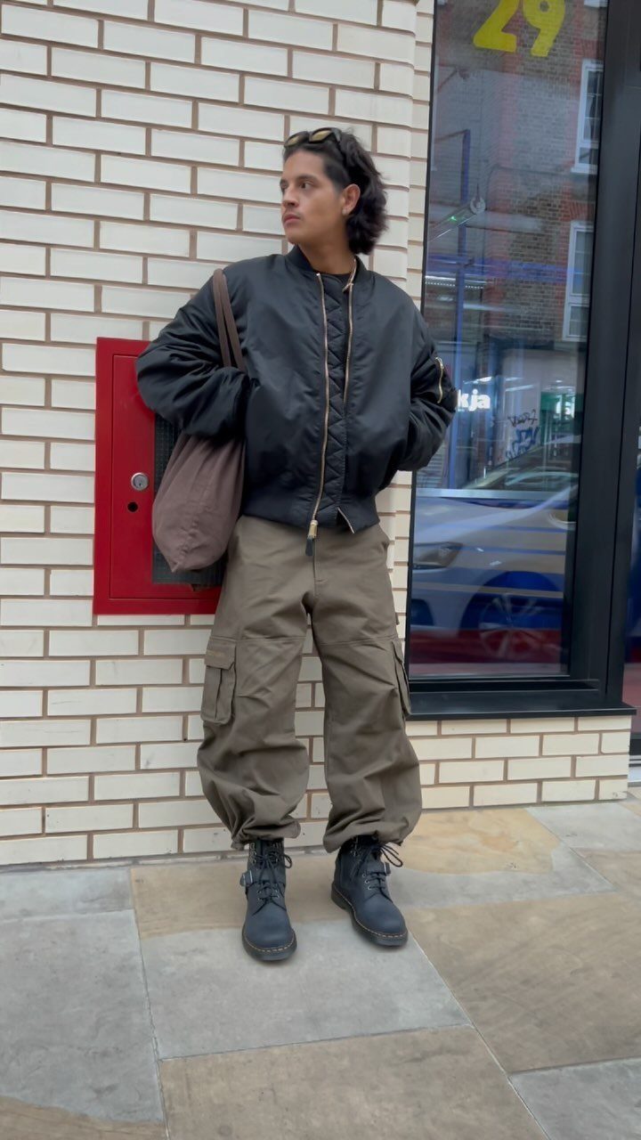 Person wearing black bomber jacket, olive cargo pants, and black lace-up boots.
