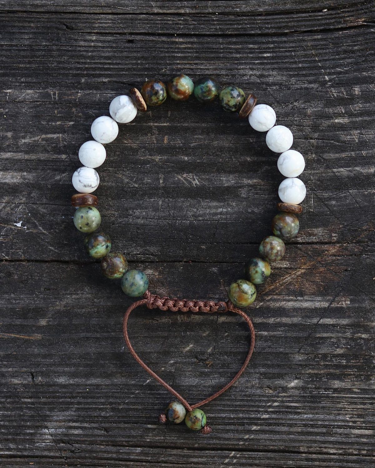 Beaded bracelet with white and green stones on a dark wooden background