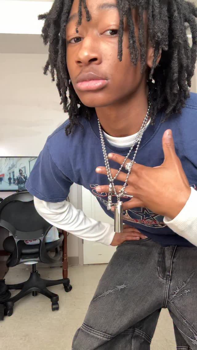 Young man wearing multiple silver chunky chain necklaces and a silver ring.