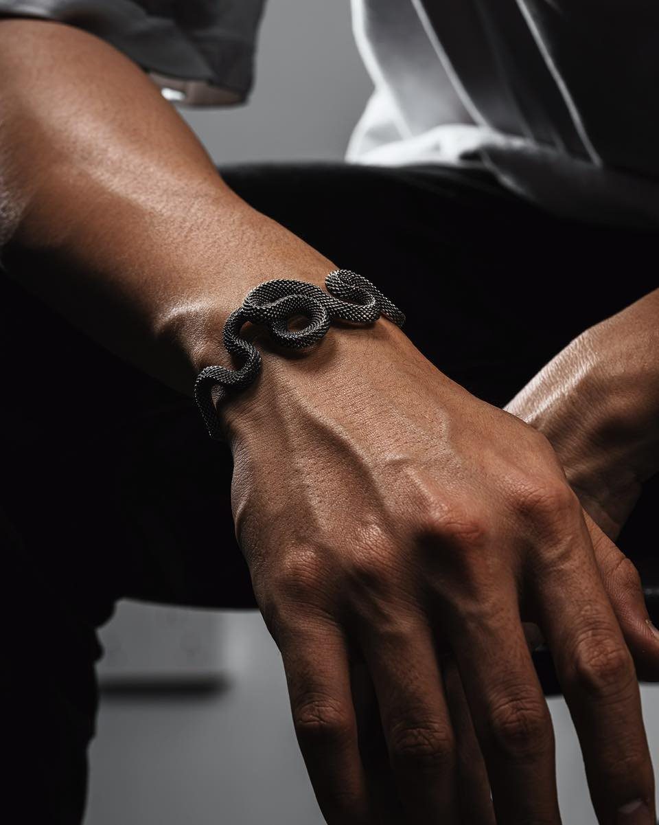 Black textured snake bracelet wrapped around a person's wrist and hand